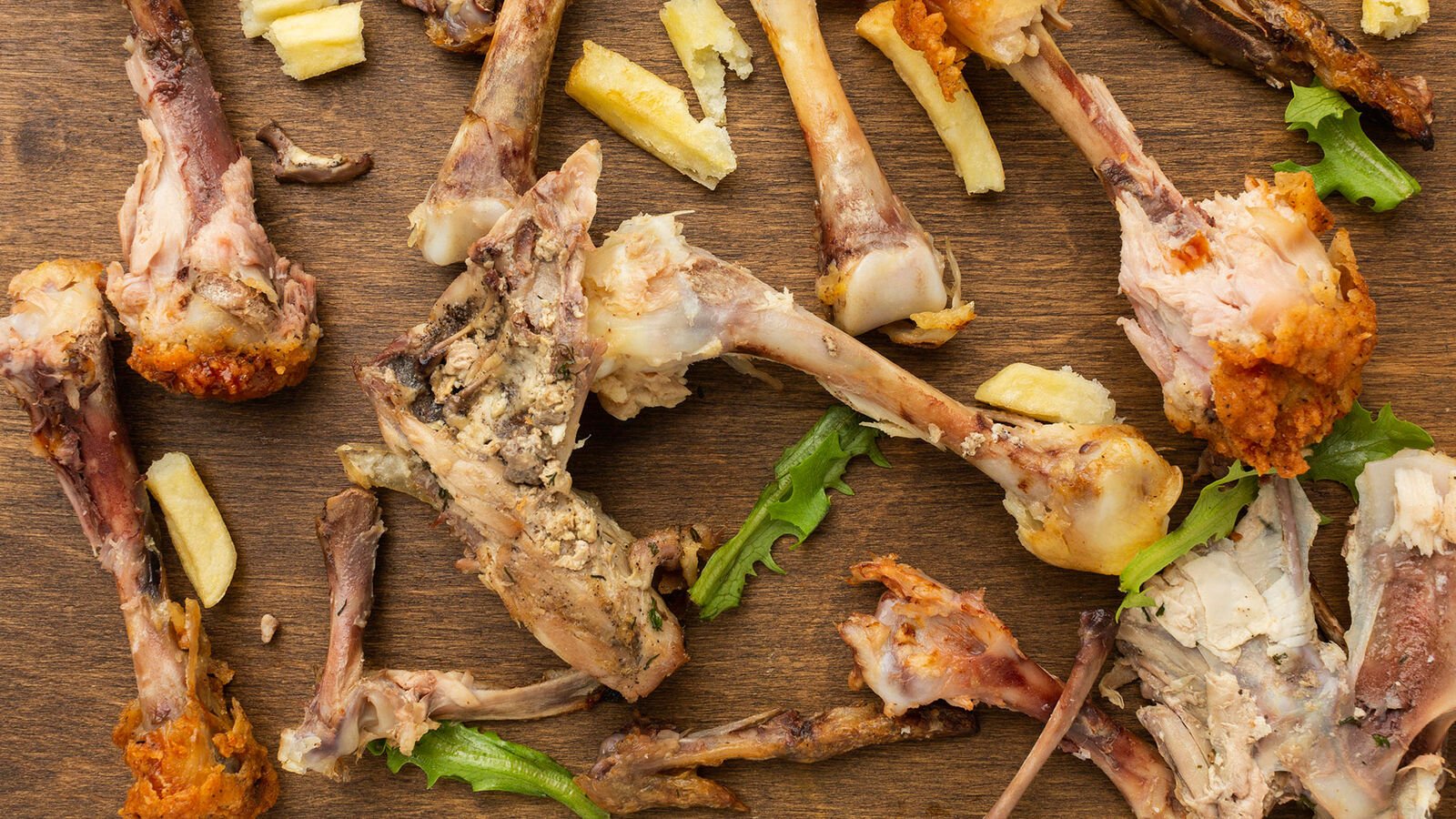 Several chewed chicken wings lie on a wooden cutting board