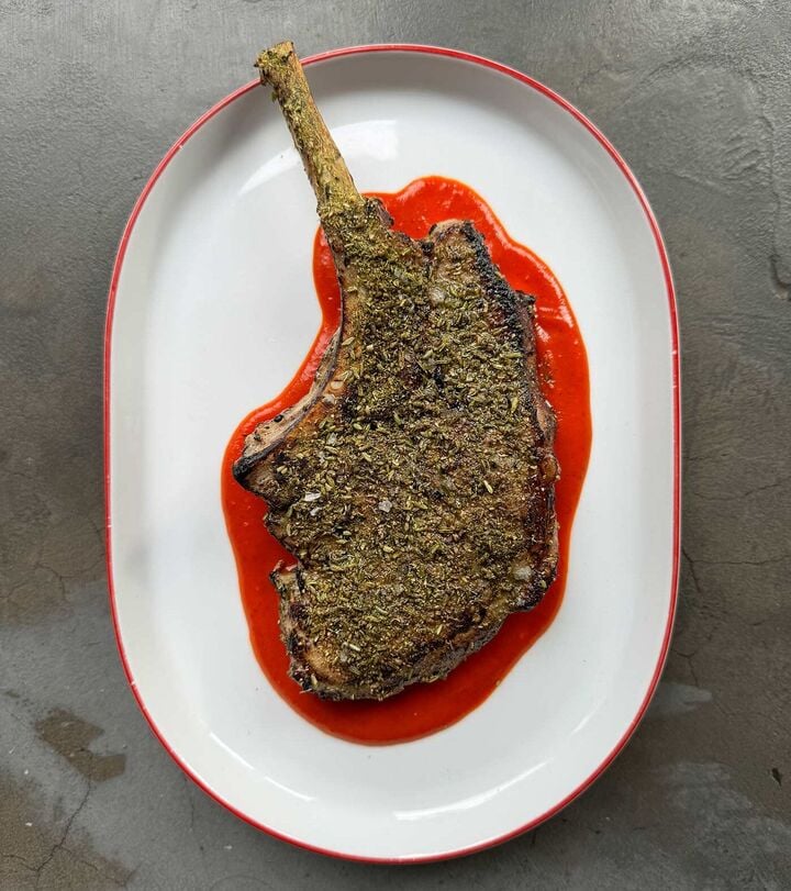 Duroc pork chop cooked until medium rare on the wood fire oven served over red Mojo sauce Duroc pork chop