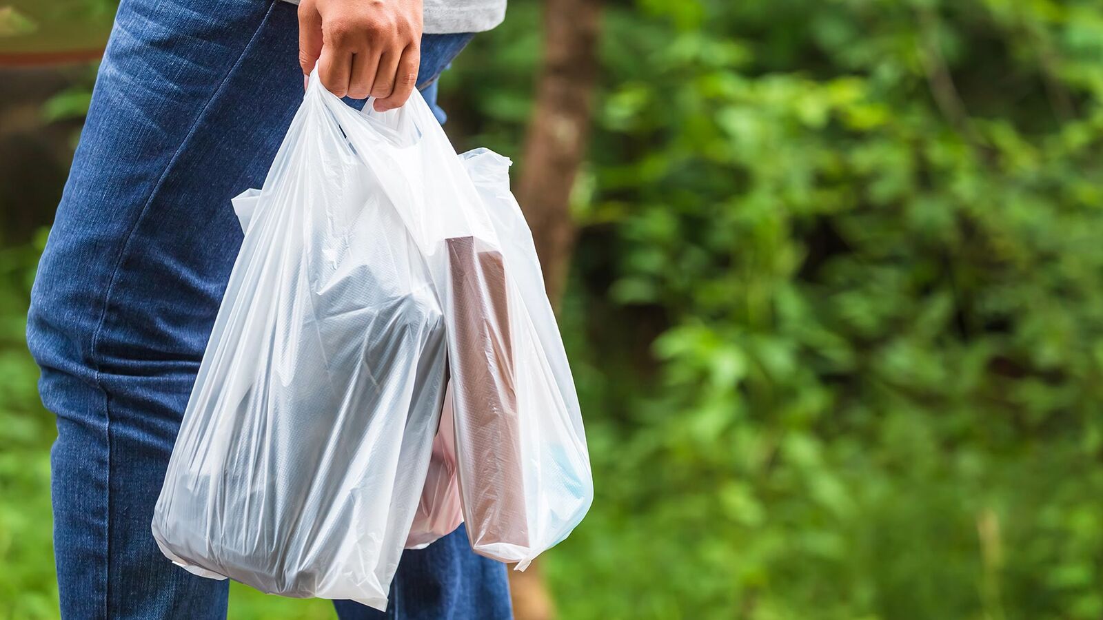 Prohibited: very thin and lightweight plastic shopping bags a man carries two thin and slightly transparent shopping bags in his left hand