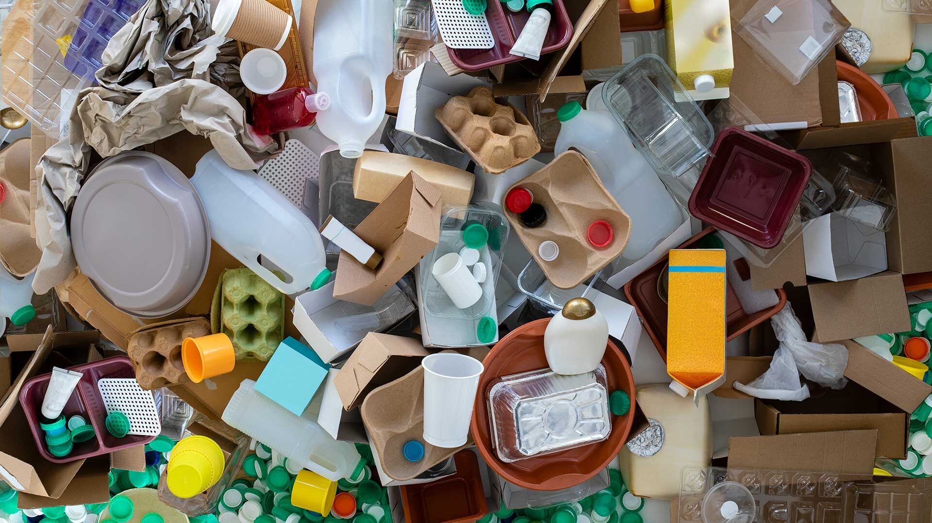 Reduction of packaging waste Various recyclable packaging such as plastic bottles, coffee cups, egg cartons, wrapping paper and plastic boxes are piled up on the floor
