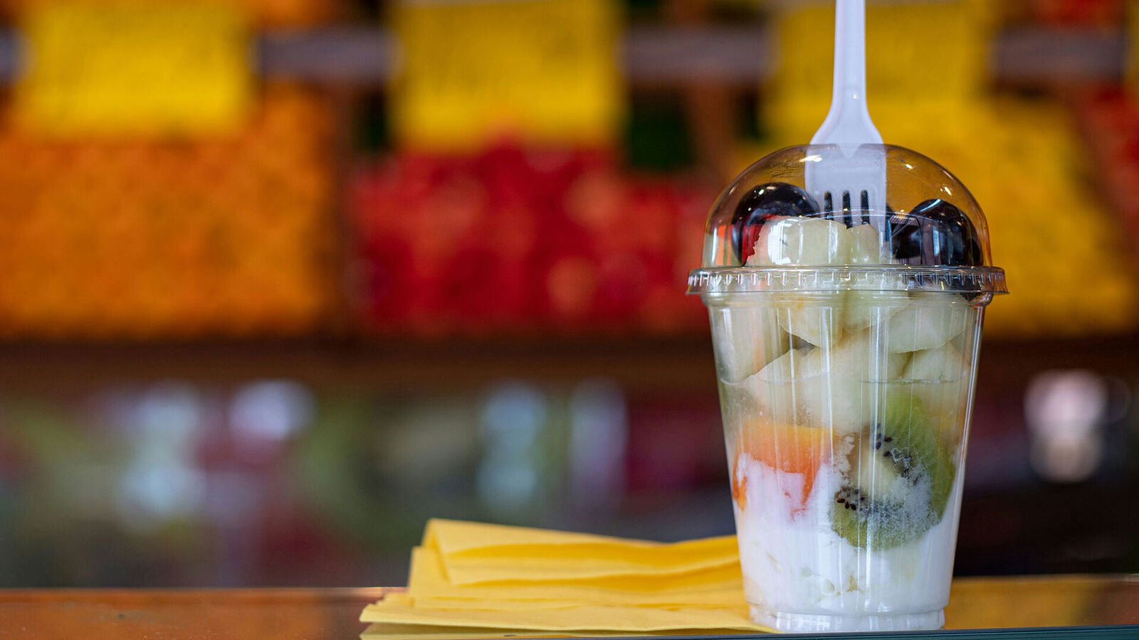 Fruit in disposable packaging: prohibited or allowed? A transparent plastic cup with fruit and yoghurt on a table