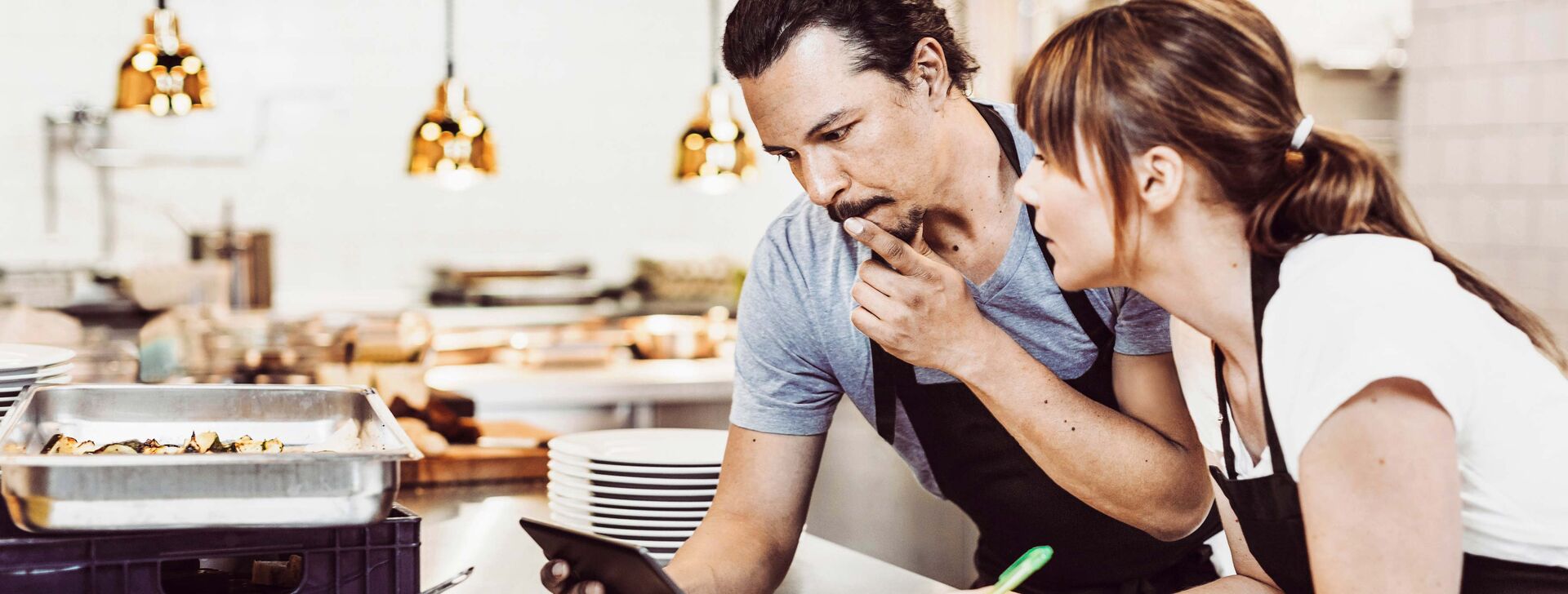 Each financing option has advantages and disadvantages Two restaurateurs stand in the kitchen and look into a tablet