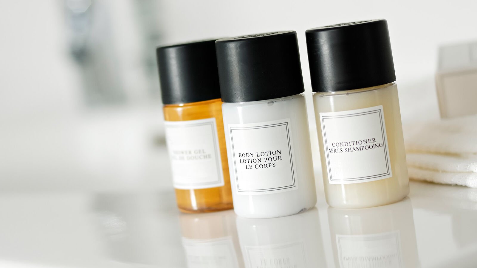Prohibited: Cosmetics, hygiene and toiletries in mini-disposable plastic packaging Three miniature bottles of shampoo, conditioner and body lotion in the bathroom of a hotel room