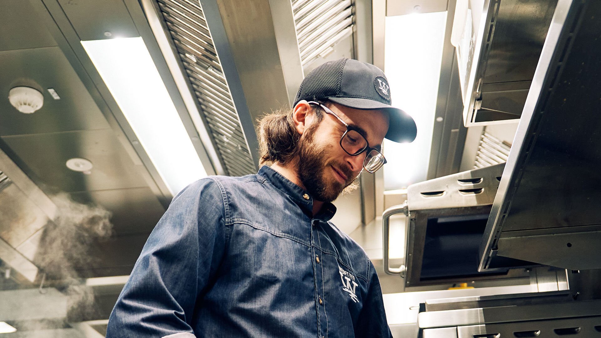 Energiespar-Tipps: rund um die Beleuchtung Ein Koch bei der Arbeit in der Gastroküche mit hellen Leuchten über ihm an der Decke