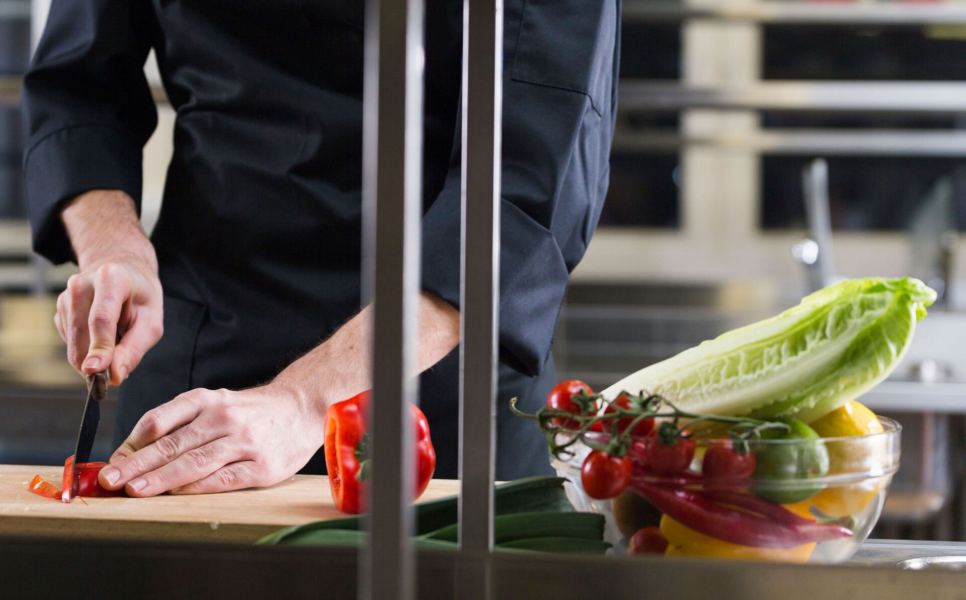 11 ideas for less food waste in foodservice In a restaurant kitchen, a chef uses a knife to chop vegetables on a chopping board