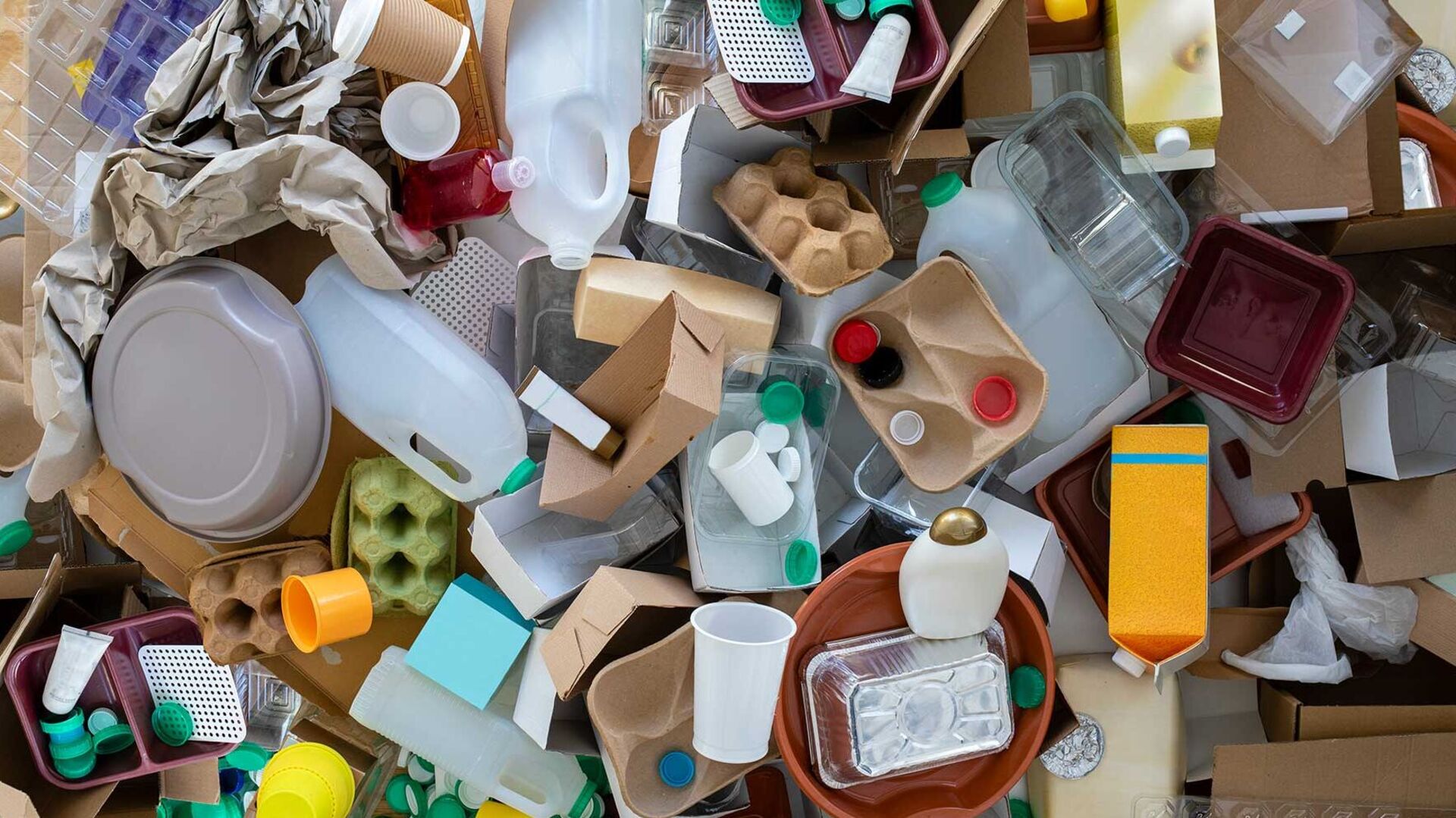 The new Packaging and Packaging Waste Regulation (PPWR) 2025 Various types of recyclable packaging such as plastic bottles, coffee cups, egg cartons, wrapping paper and plastic boxes are piled up on the floor