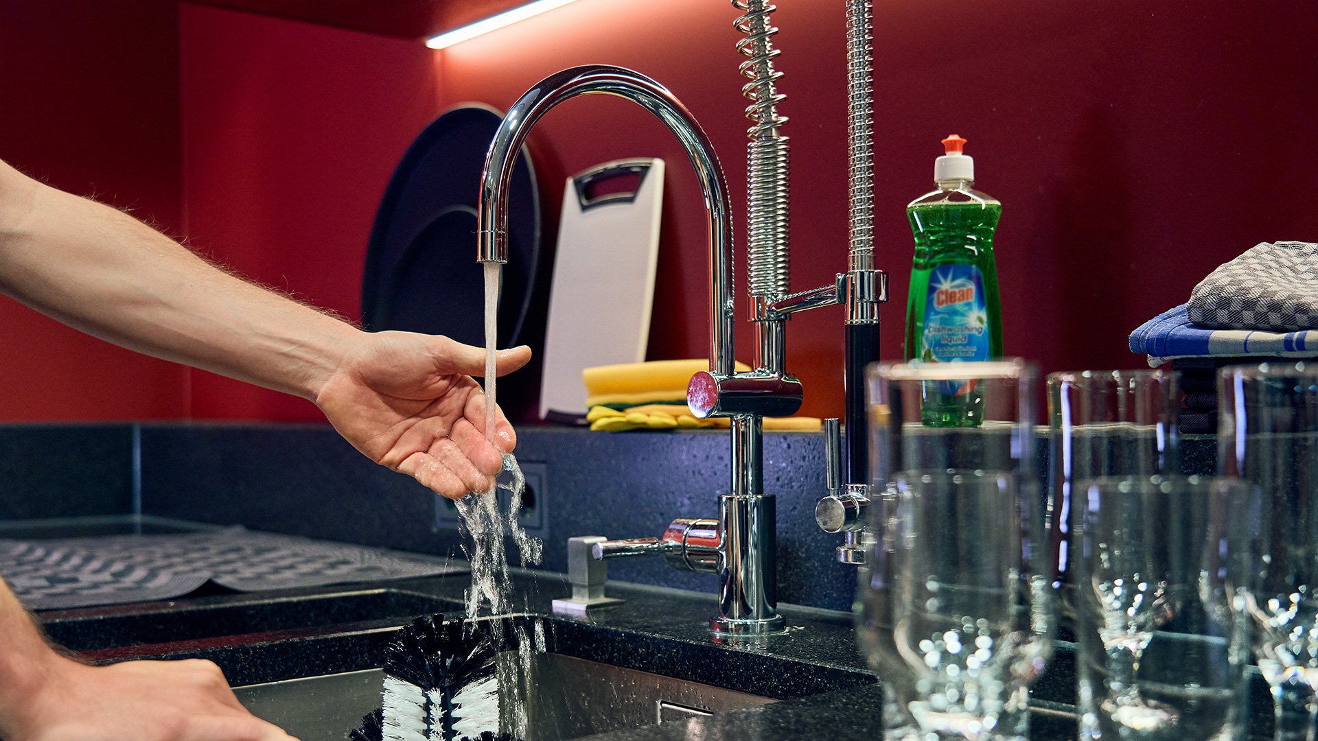 Nachteil beim Handspülen von Gläsern: zu niedrige Temperatur Mann steht am Spülbecken einer Gastro-Theke und hält zur Prüfung der Temperatur eine Hand unter das einlaufende Wasser